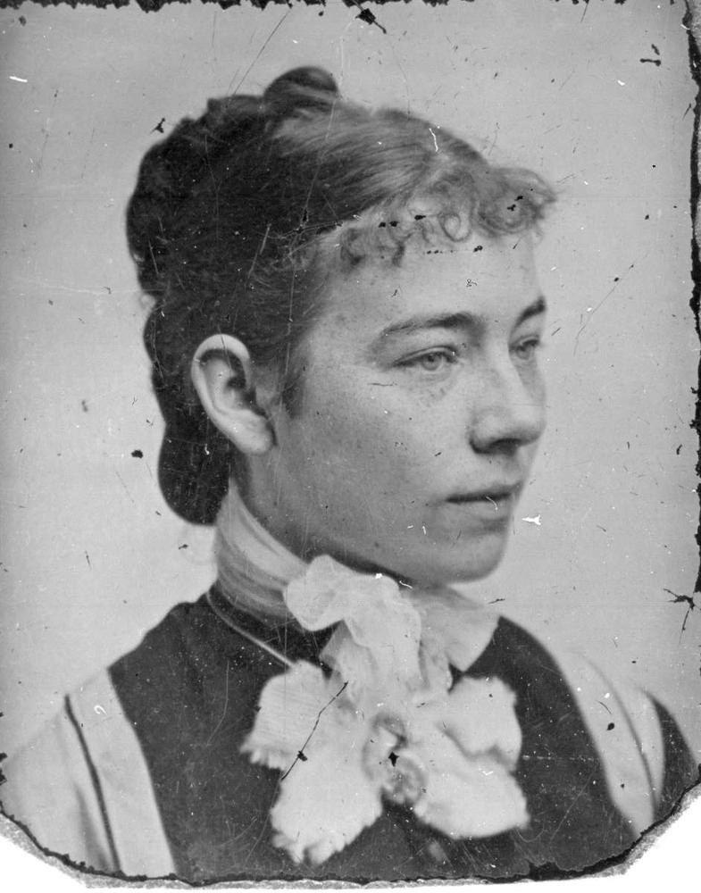 A black-and-white portrait of a young woman in three-quarter profile with a lace jabot, scratched and specked