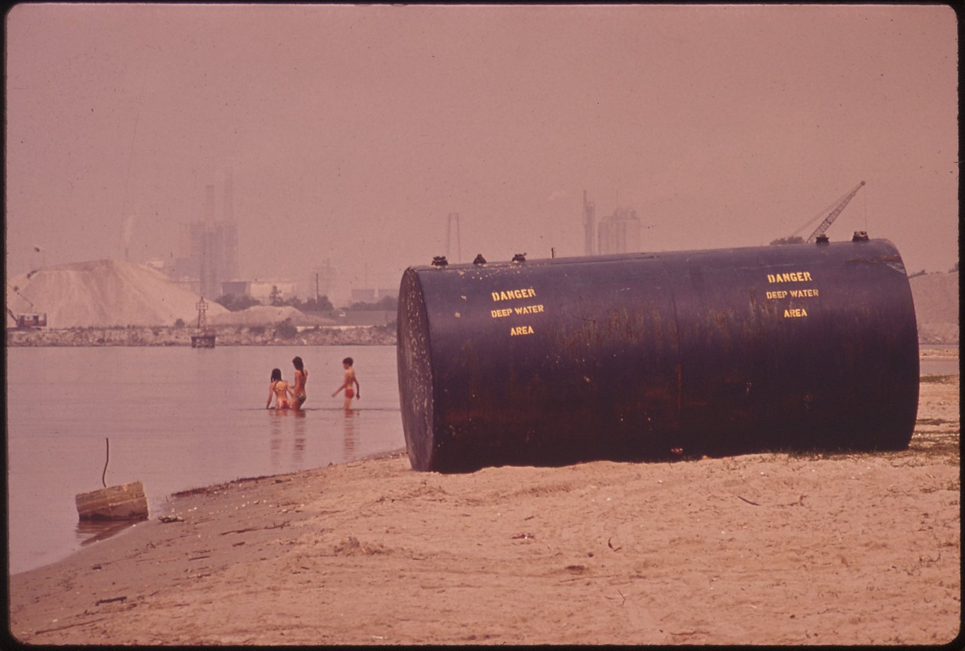 A color photograph of a beach and a large tank, everything faded to an overall pink