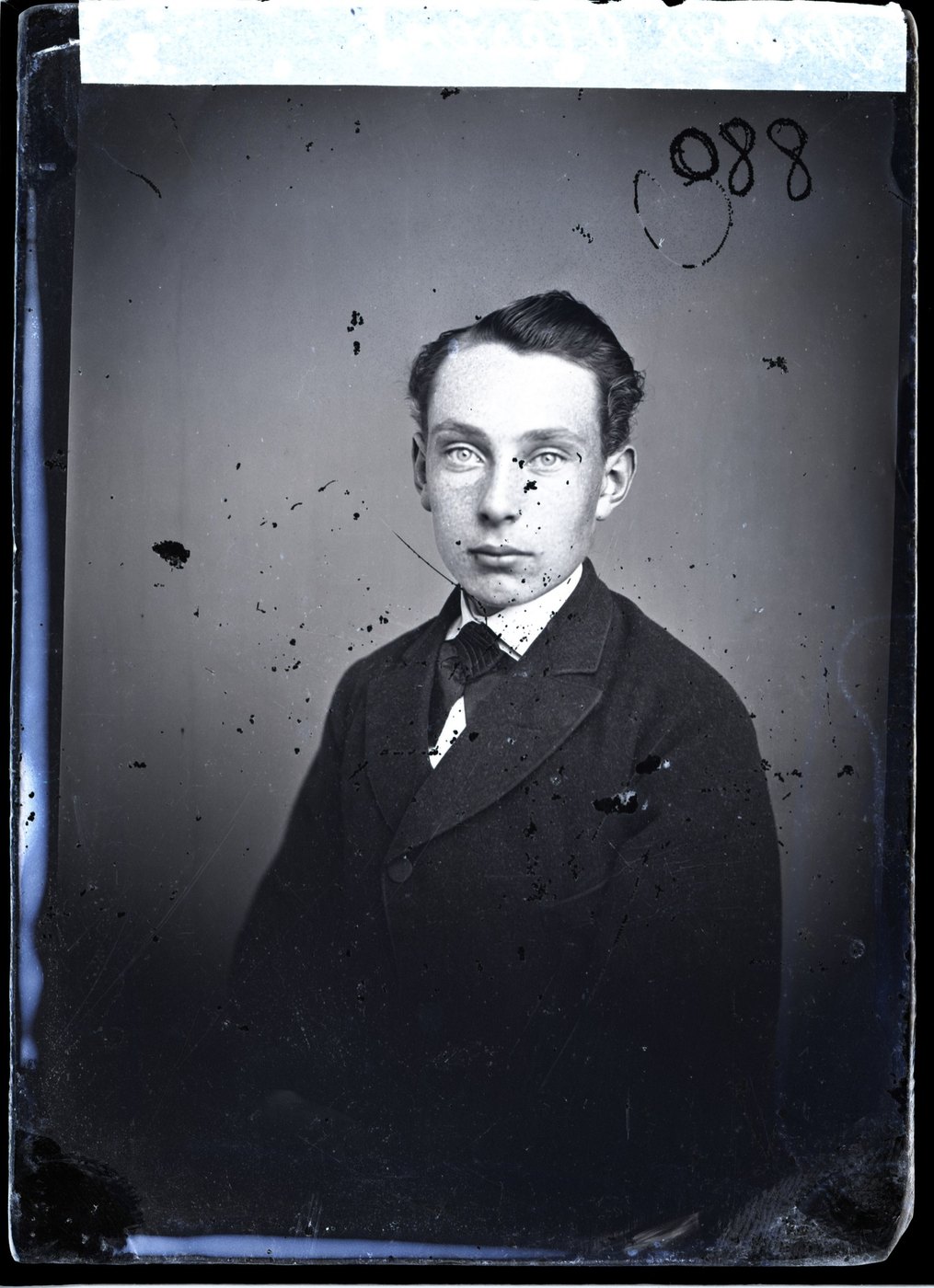 A glass plate portrait of a young man, speckled with black flecks of lost emulsion