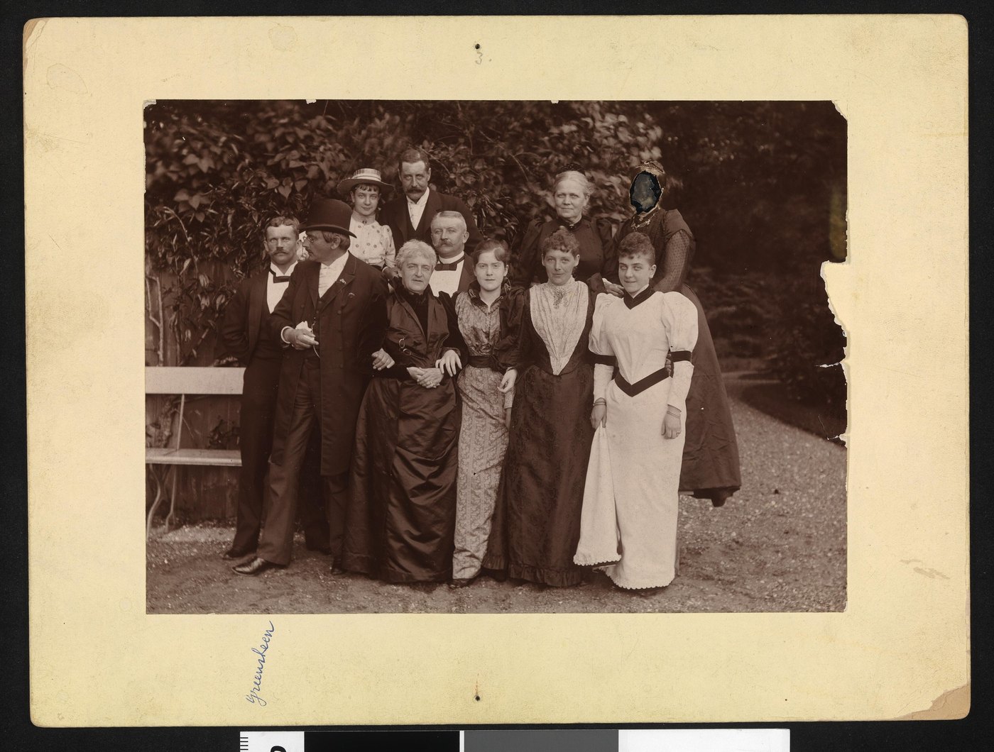 A mounted group portrait from the 1890s with a piece torn from the right-hand edge of the print