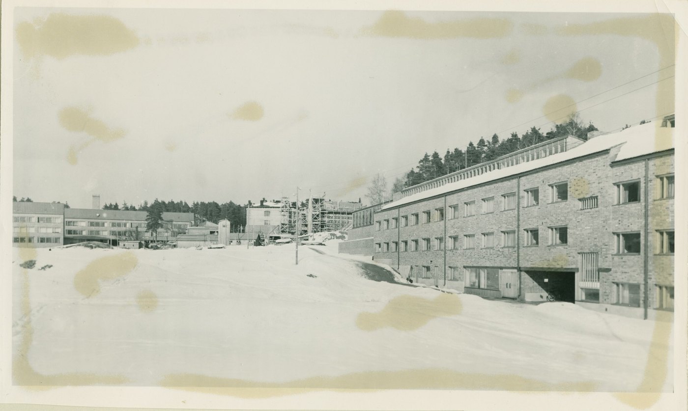 A photograph of snow and apartment buildings, blotched all over with yellow-brown damp stains
